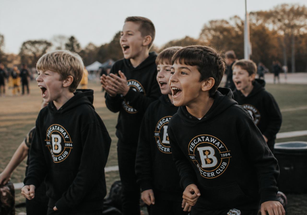 Youth soccer team cheering in matching custom black hoodies